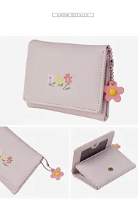 Detail view of pink floral tri-fold wallet showing interior card slots and flower charm