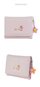 Floral print tri-fold wallet detail with delicate flower pendant and soft texture