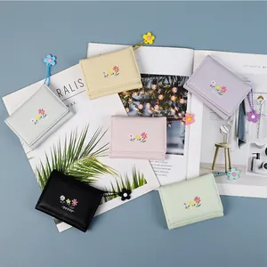 Floral mini trifold wallets in candy colors with flower pendant charms on magazine background