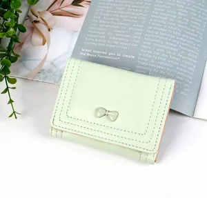 Close-up of mint green wallet with bow detail and high-quality stitching on leather