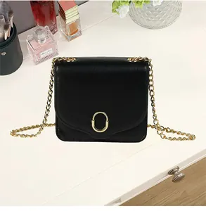 Detailansicht einer schwarzen Leder Mini Tasche mit goldenem Oval Verschluss auf weißem Tisch