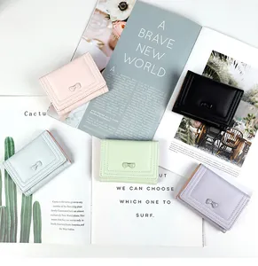 Short tri-fold wallets in pastel colors with cute bow decoration on an open magazine