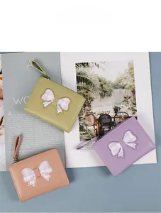 Three multi-colored bow short wallets in mint, purple, and pink on magazine