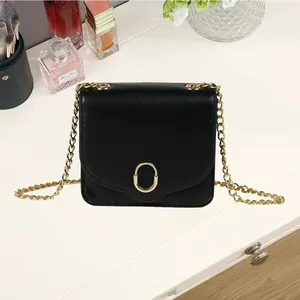 Schwarze Umhängetasche aus Leder mit goldener Schnalle und Kette auf weißem Schreibtisch