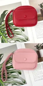 Detail view of lychee-patterned coin purses in red and pink with wrist straps and key rings