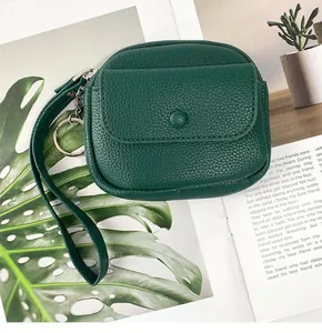 Macro view of dark green pebbled leather coin purse with wrist strap and metal keychain