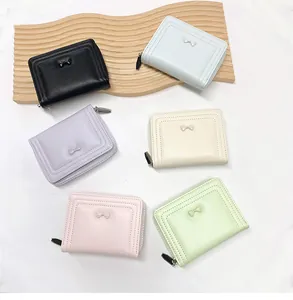 Flat lay of small pastel bow wallets in black, blue, purple, beige and green colors