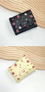 Détails des motifs de fraises et nœuds sur les portefeuilles noirs et jaunes