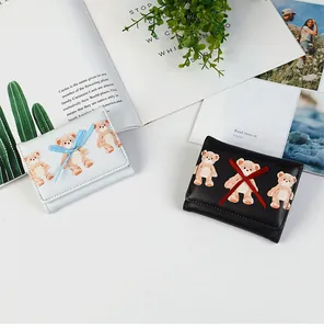 Detail of cute trifold wallets with teddy bear prints and 3D ribbon bows on a desk