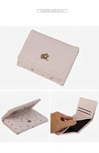 Détails du portefeuille rose montrant les fentes pour cartes et la boucle fleurie dorée
