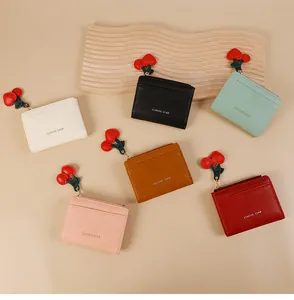 Vue à plat de petits portefeuilles en cuir coloré avec pendentifs cerise et zip