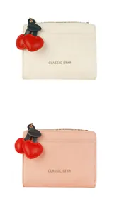 Détail de petits portefeuilles crème et rose avec breloques cerise en cœur