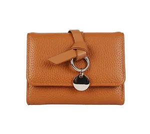 Détail d'un portefeuille marron en cuir grainé avec nœud décoratif et pendentif argenté