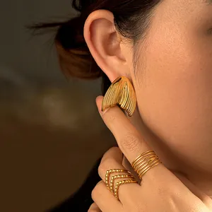 18k gold plated mermaid tail stud earrings with matching layered rings on a female model