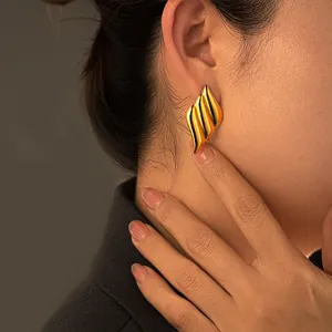 Gold plated stainless steel liquid heart winged earrings worn on female model side profile