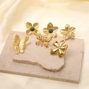 Golden butterfly and flower rings set with green emerald stones on a stone base