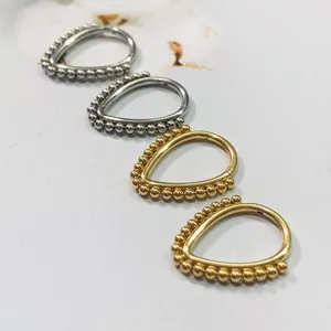 Macro detail of drop-shaped 316L stainless steel piercing rings with beaded edge in gold and silver