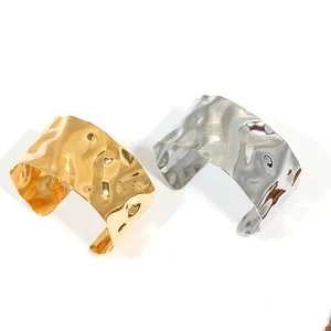 Macro shot of gold and silver cuff bracelets with hammered texture and water wave design