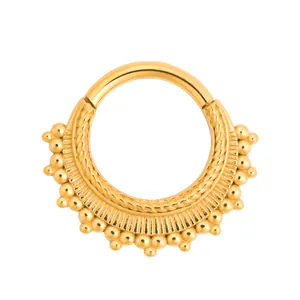 Ethnic gold septum clicker ring with braided texture and beaded details on white background