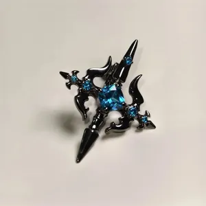 Macro shot of gun-black gothic cross ring with square blue gemstone and crystal accents