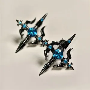 Macro detail of gothic cross earrings with bright blue gemstones in black metal finish