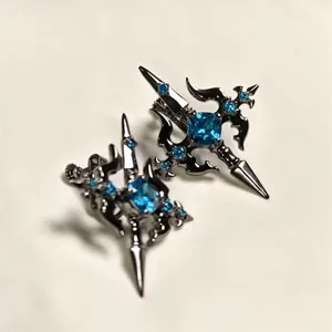 Macro view of gothic cross sword earrings with blue stones and screw-back clips