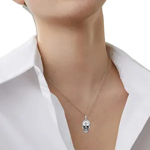 Collier avec pendentif tête de mort et croix gothique argentée porté sur une chemise blanche