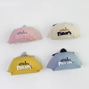 Détail de chapeaux de soleil bébé en quatre couleurs avec design de dinosaure