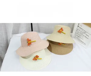 Vue à plat de quatre chapeaux de paille colorés pour enfants avec décor de libellule pour l'été