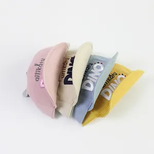 Détail de quatre casquettes de baseball en toile pour bébé avec broderie dino et visière