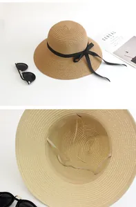 Detailed close-up of woven straw hat texture with black ribbon bow and windproof strap