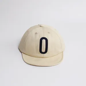 Détail de la lettre brodée bleu marine sur une casquette en coton beige pour enfant