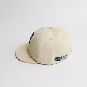 Détail du chapeau de soleil beige en coton pour bébé avec écusson et évents d'aération