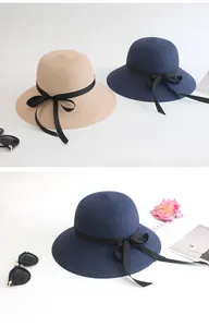 Detail of woven straw sun hats with black ribbon bows in light beige and navy blue