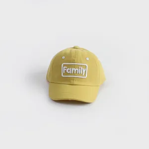 Detail of yellow cotton canvas baseball cap with white Family embroidery on a clean background