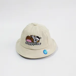 Detail of baby sun hat with cute cartoon cow embroidery and Happy Cow text on beige canvas
