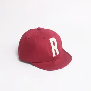 Détail d'une casquette rouge pour enfant avec écusson lettre R blanche en coton doux