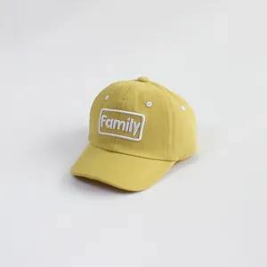 Detailed close-up of yellow cotton baseball cap with Family embroidered patch and vent holes