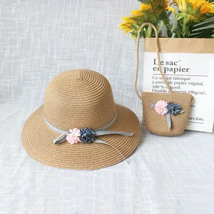 Detail von Strohhut und passender Tasche mit Blumenakzenten und gepunkteten Bändern