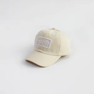Detail of beige cotton baseball cap featuring white embroidered Family patch design