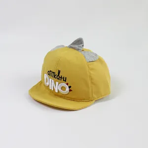 Detail of yellow toddler baseball cap featuring DINO embroidery and grey 3D dinosaur fins