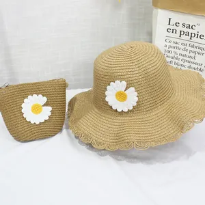 Dettaglio del set cappello e borsa in paglia con ricamo a margherita e bordo ondulato