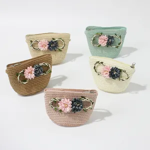 Detail of five colorful woven straw pouches featuring 3D floral accents and metal zippers