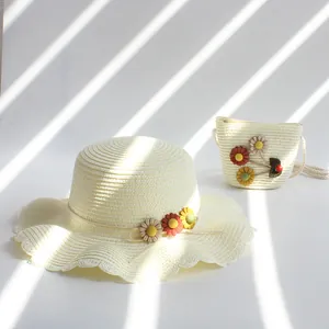 Détail de l'ensemble chapeau de paille crème et sac enfant avec fleurs 3D et bord ondulé