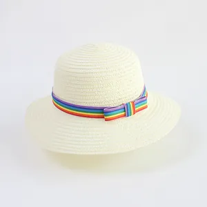 Detail of straw hat featuring rainbow ribbon and bow decoration on cream woven material