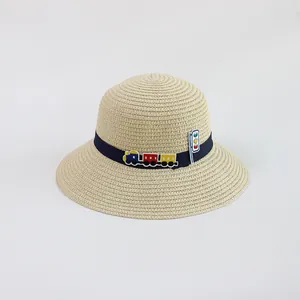 Dettaglio cappello di paglia bimbo con trama beige e decorazione a forma di trenino