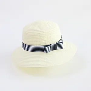 Close-up of finely woven cream straw hat texture and blue striped ribbon bow