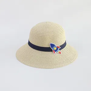 Dettaglio di un cappello di paglia per bambini con nastro blu e ricamo a forma di razzo