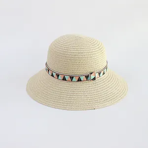 Close-up of beige straw hat featuring colorful geometric pattern band and fine woven texture