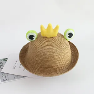 Detailed view of woven straw sun hat for kids with frog eyes and a yellow plush crown